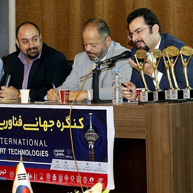 Dana Bina on an expert panel at an international smart technologies congress, seated beside award trophies
